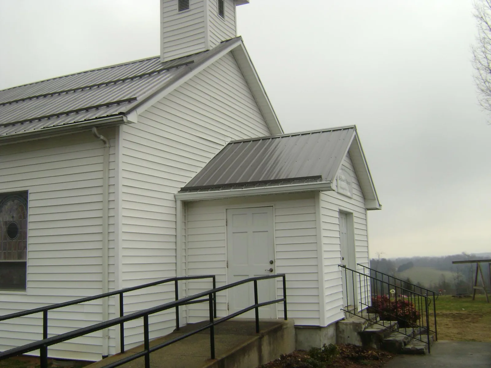 Gray metal roof on a white clapboard church with a steeple in New Hampton